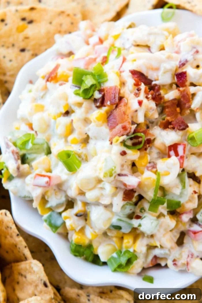 Loaded Cheesy Bacon Ranch Corn Dip 2 Overhead view of a creamy Bacon Ranch Corn Dip in a white serving dish, surrounded by golden tortilla chips, invitingly ready for a party.
