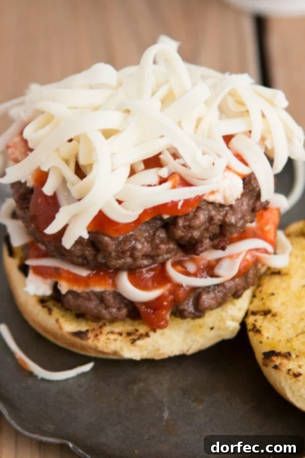 Building the perfect Lasagna Burger with ricotta, sauce, and mozzarella. Detailed shot of the Lasagna Burger being assembled, showing the creamy ricotta, vibrant red sauce, and shredded mozzarella cheese ready to be layered on the seasoned Italian beef patty.