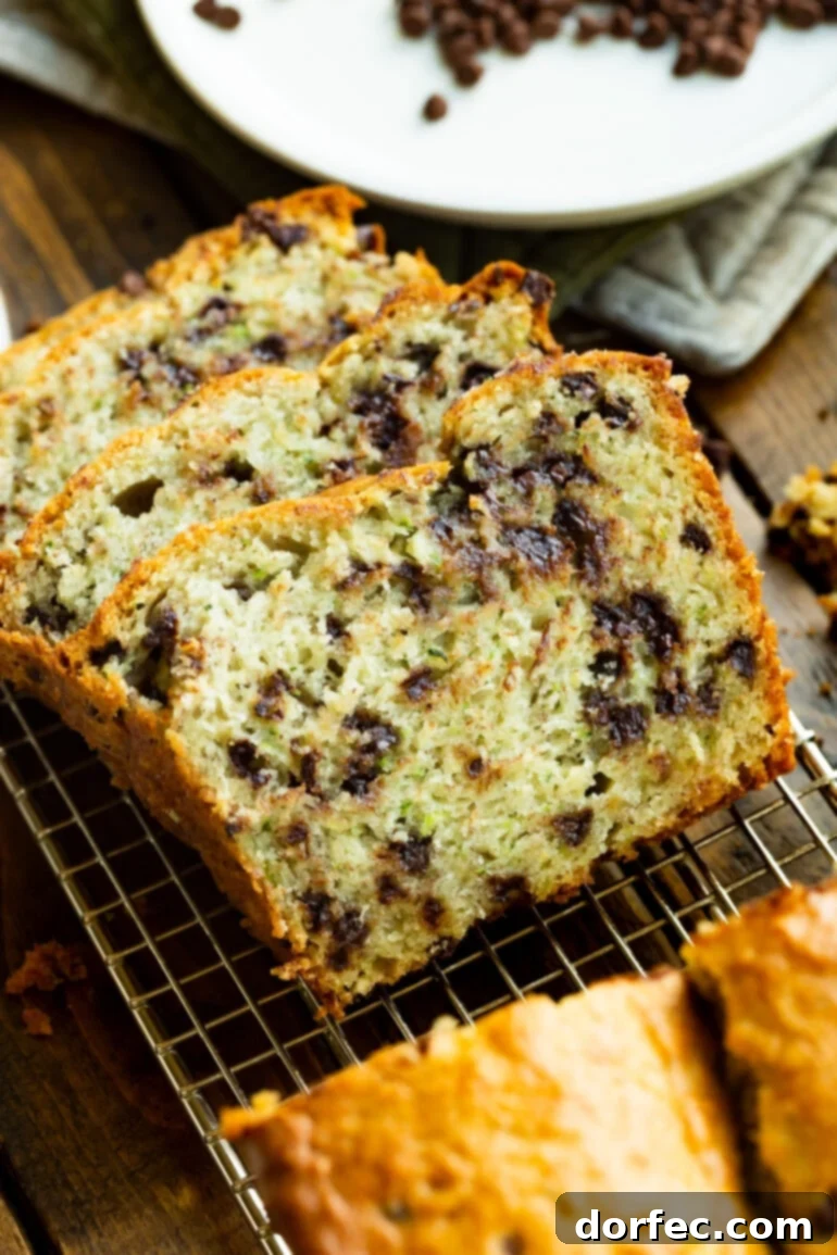 Three thick slices of chocolate chip banana zucchini bread stacked against each other, showcasing their moist texture and generous chocolate chips.