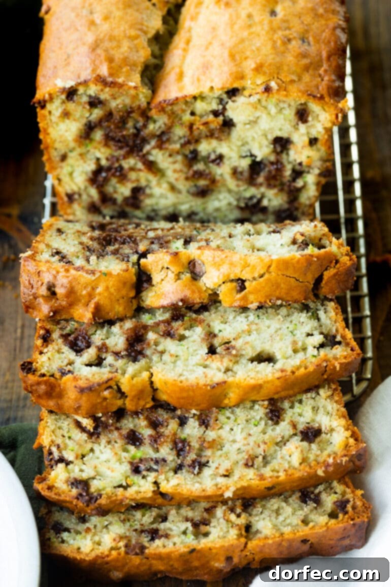 A freshly baked loaf of chocolate chip banana zucchini bread with several slices cut and arranged, highlighting the golden crust and moist interior.