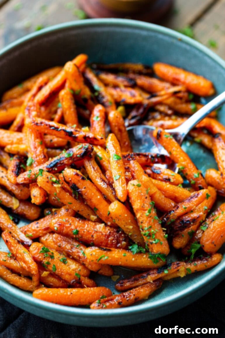 A large silver serving spoon gracefully scooping a generous portion of golden roasted honey glazed carrots from a bowl.