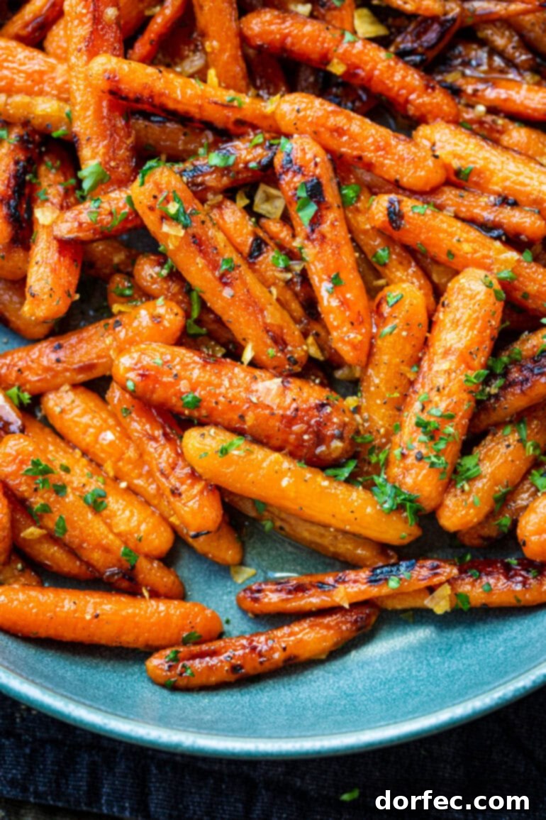 A vibrant close-up of roasted honey glazed baby carrots, artfully topped with finely chopped parsley and minced garlic.