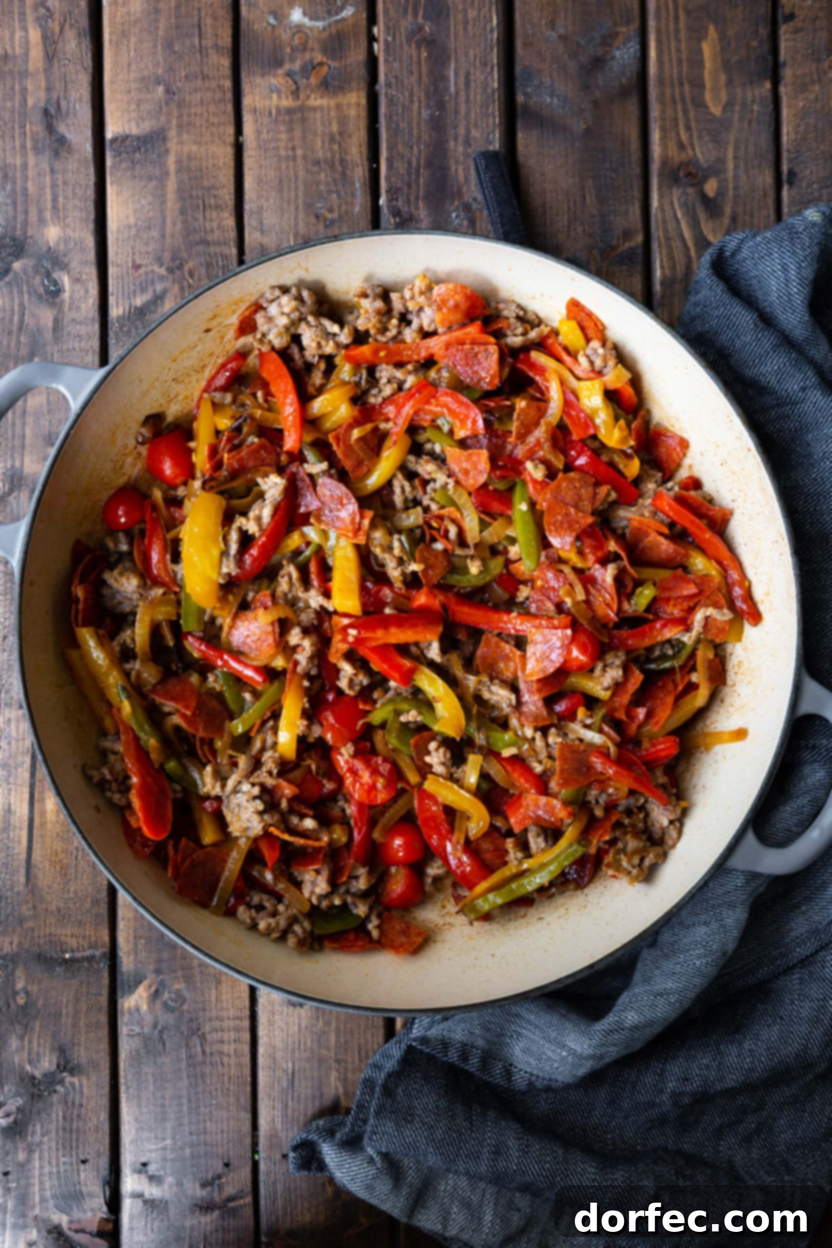A photo of cooked Italian sausage and caramelized peppers and onions. There's nothing better than the savory combination of sausage, sweet peppers, and tender onions, especially when featured in this delightful pasta recipe for an easy weeknight dinner.