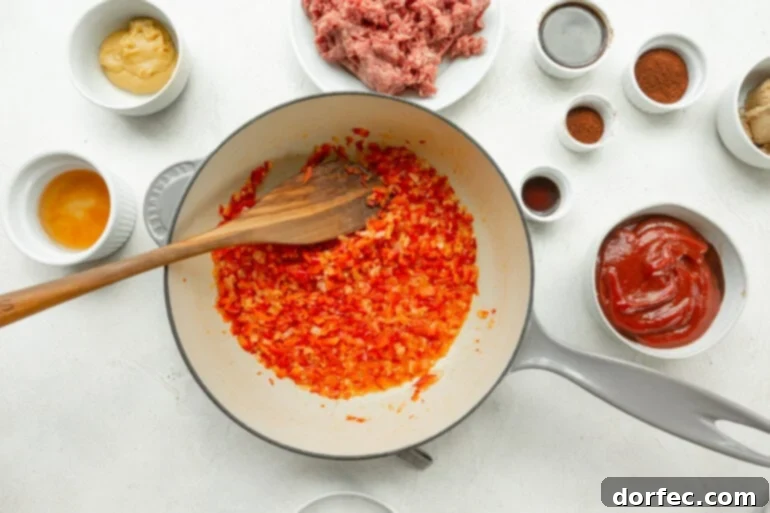 Freshly diced onions and red bell peppers are sautéing in a sturdy Dutch oven, surrounded by all the vibrant ingredients needed to create the best homemade sloppy joes.