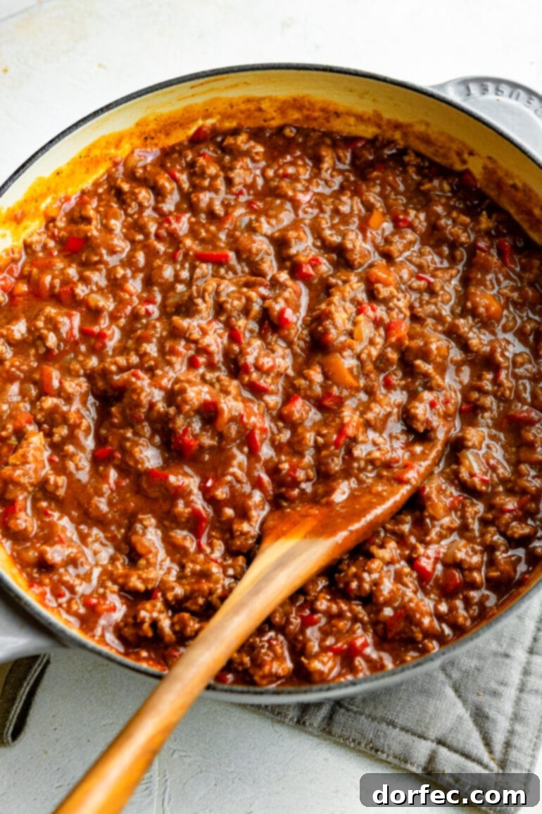 A large Dutch oven brimming with the rich, saucy sloppy joe mixture, with a wooden spoon resting in the pot, ready to serve.