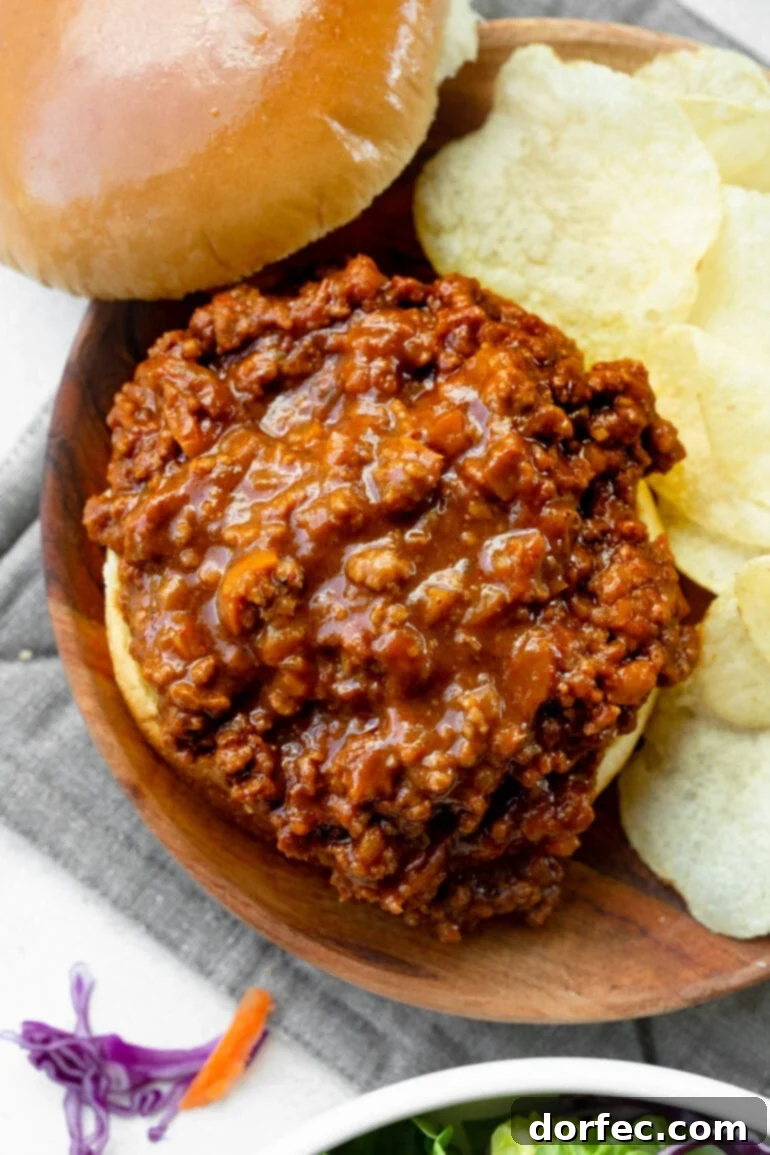 An overhead shot of a messy, delicious sloppy joe sandwich with the top bun removed, showcasing the generous serving of saucy ground beef filling.