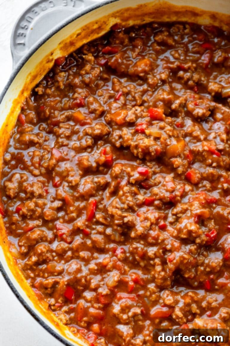 A Dutch oven filled to the brim with rich, saucy sloppy joe filling, ready to be scooped onto buns.