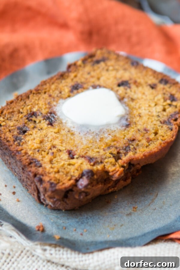 A perfectly baked loaf of pumpkin chocolate chip bread on a cooling rack, ready for slicing.
