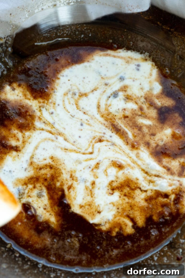 A photo of heavy cream pouring into a dark brown syrup, illustrating the creation of the apple crisp sauce.