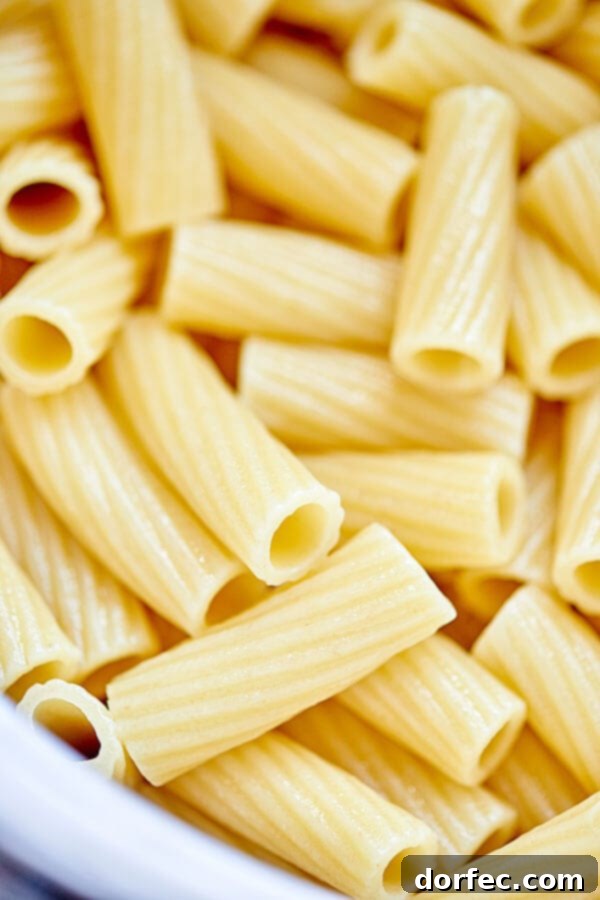 A large baking pan filled with Spicy Sausage Rigatoni, freshly mixed with marinara and ready to be smothered in mozzarella and baked to perfection.