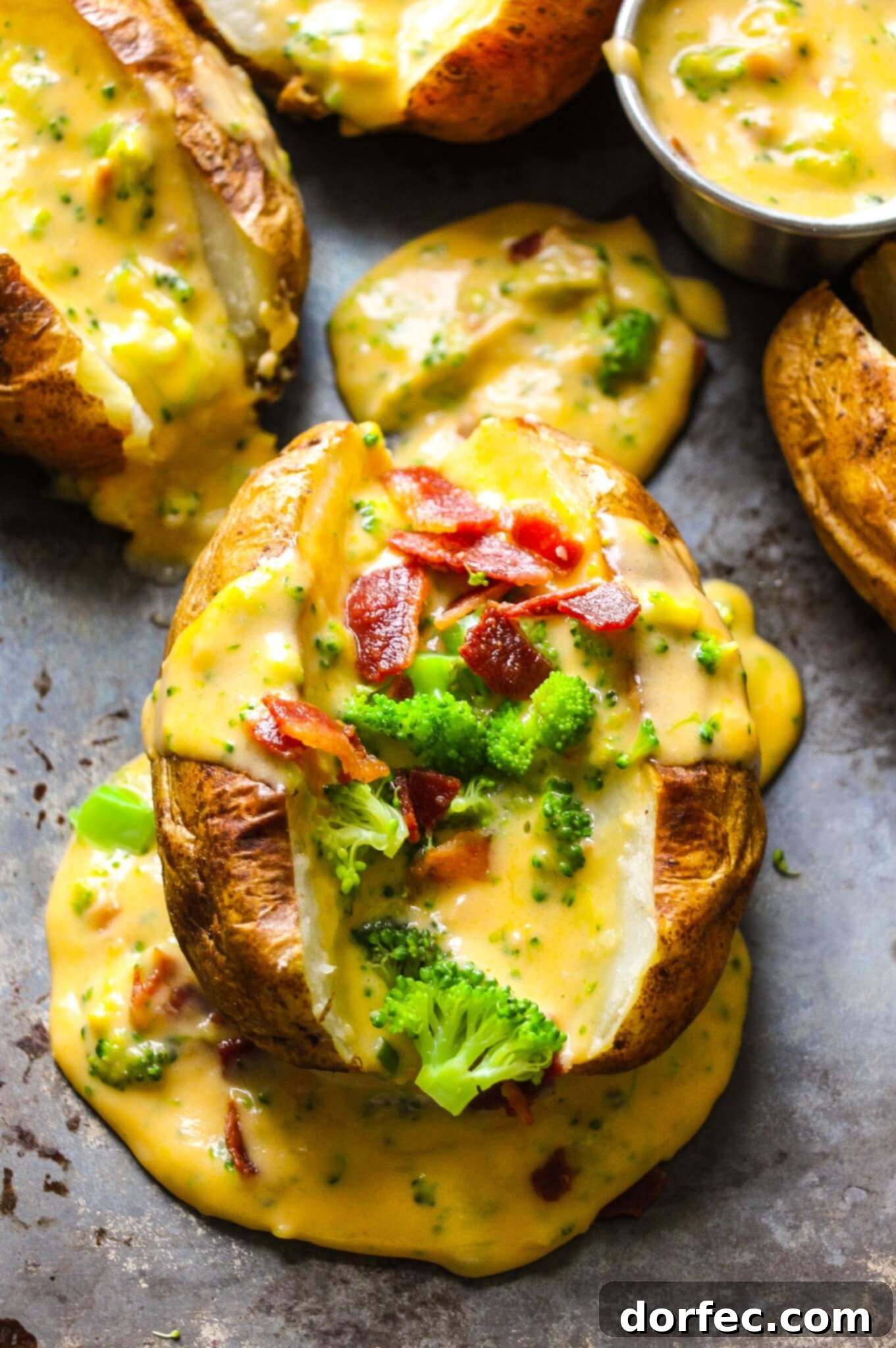A baked potato sliced in half, open, and stuffed with broccoli, bacon crumbles, and topped with rich, homemade cheese sauce, presented beautifully.