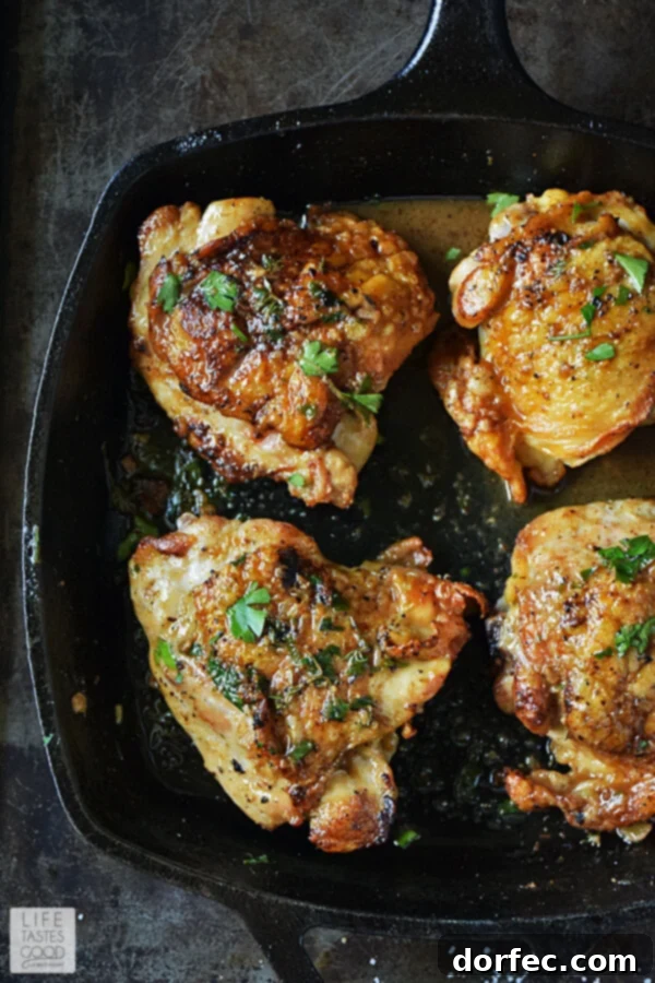 Golden brown pan-roasted chicken thighs in a skillet, bathed in a vibrant herb butter sauce, with fresh parsley and thyme garnishing the dish. The chicken skin is visibly crisp, inviting you to savor its perfection. This dish is budget-friendly, low-carb, and perfect for New Year's resolutions.