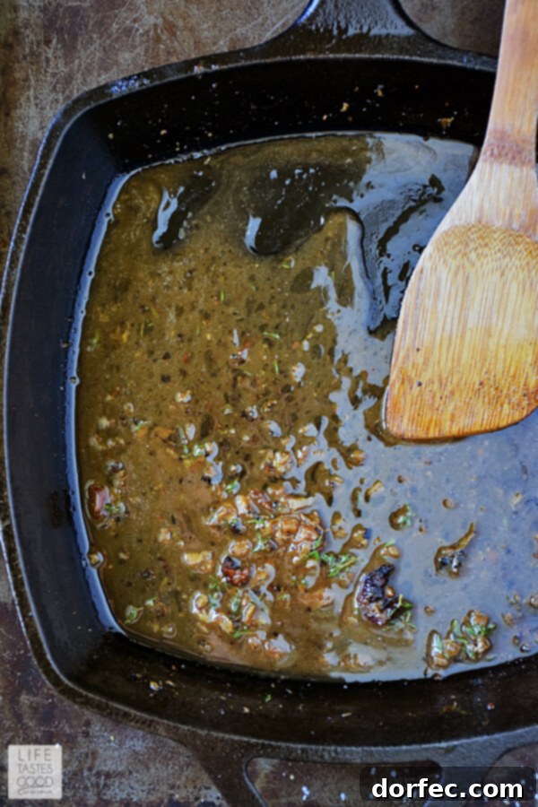 A close-up of the finished herb butter sauce simmering in a cast-iron skillet, enriched with melted butter, fresh parsley, and thyme. The sauce is golden, glistening, and perfectly emulsified, ready to coat the pan-roasted chicken thighs.