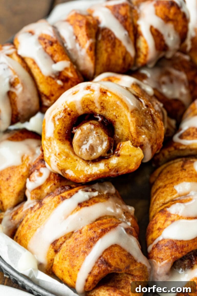 Cinnamon Roll Sausage Poppers 9 A delicious cross-section of a cinnamon roll sausage dunker, revealing the juicy sausage inside the sweet, swirled dough, with several whole dunkers blurring in the background.