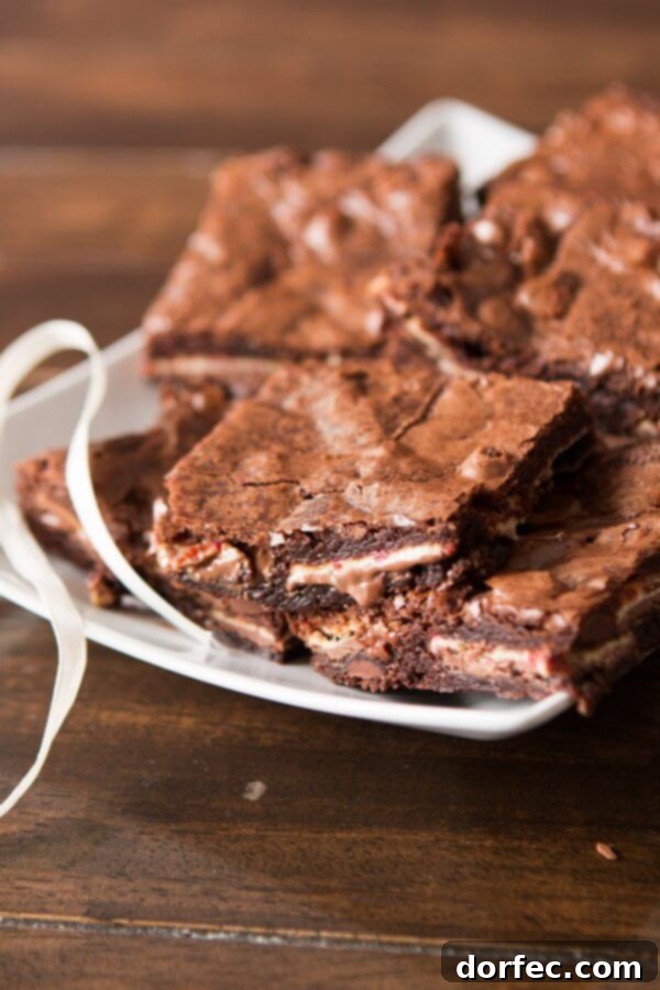 A close-up of a Ghirardelli Peppermint Bark Brownie with a bite taken out, revealing the soft, gooey peppermint chocolate center.