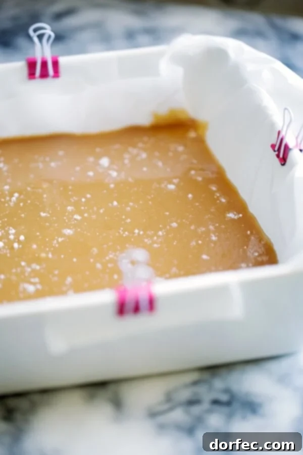 Unwrapping Soft Microwave Caramels A hand gently unwrapping a soft, chewy microwave caramel, showcasing its perfectly set texture.
