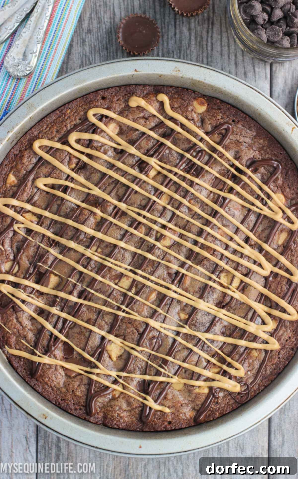 The Fudgy Peanut Butter Brownie Cake adorned with a beautiful chocolate and peanut butter drizzle, highlighting visible mix-ins.