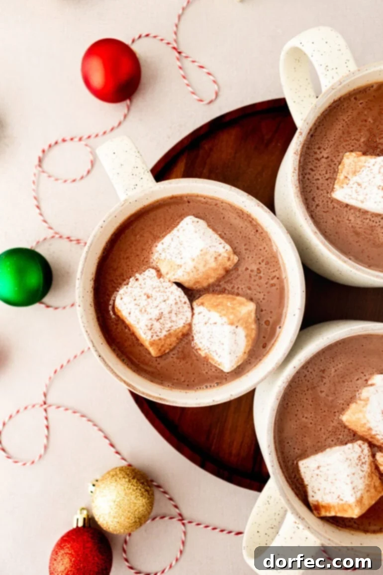 Velvety Homemade Hot Chocolate Perfection 2 A photo taken over the top of three mugs of creamy hot cocoa, each with 3 large marshmallows floating in them, inviting warmth and comfort.