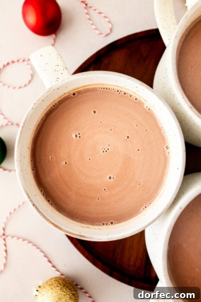 Velvety Homemade Hot Chocolate Perfection 5 An inviting overhead view of three mugs filled with creamy, homemade hot chocolate, ready to be enjoyed as a delightful winter beverage.