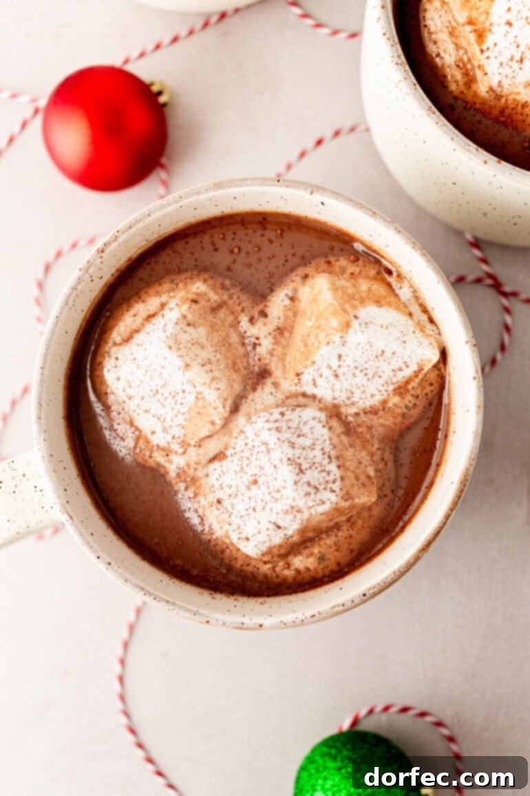 Velvety Homemade Hot Chocolate Perfection 8 An inviting overhead shot of a single white mug of homemade hot chocolate, elegantly topped with three large, fluffy marshmallows, ready for a cozy moment.