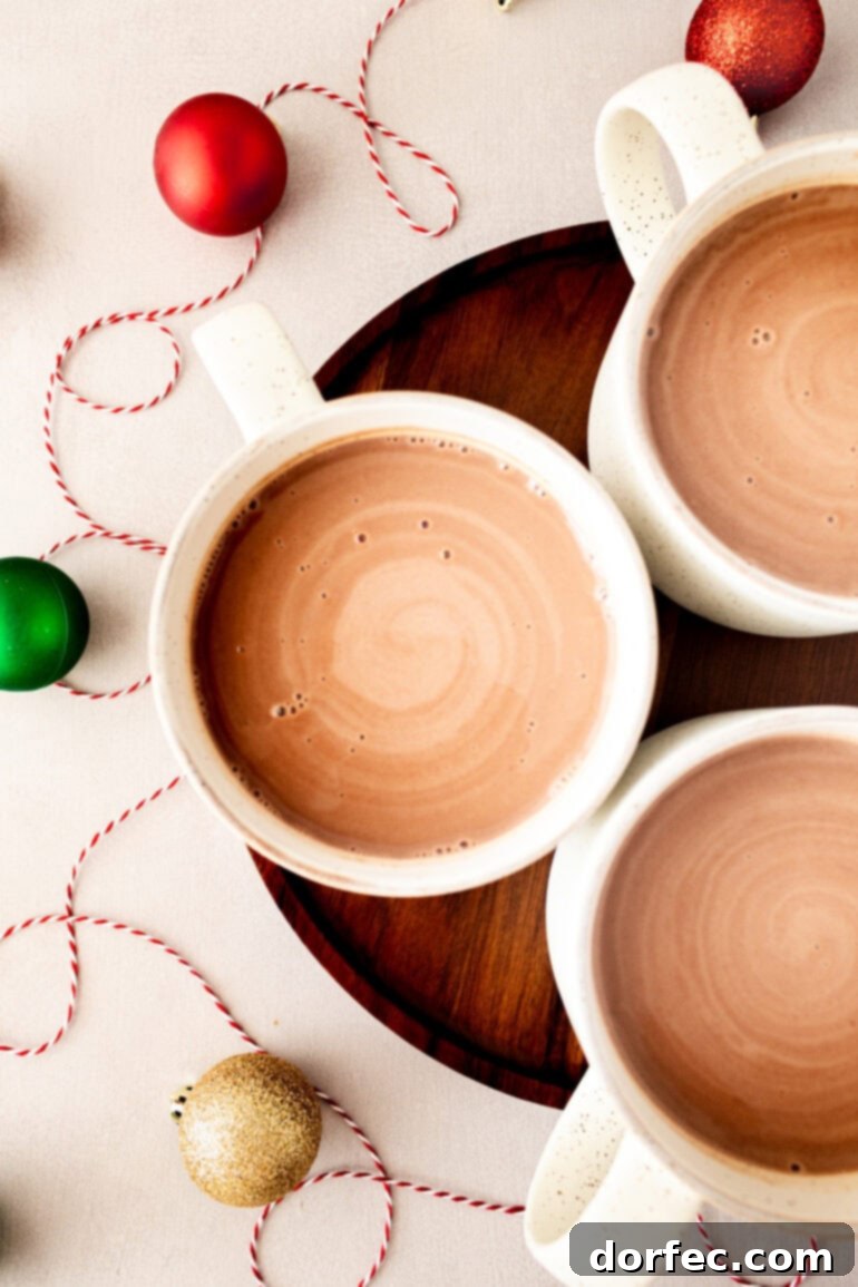 Velvety Homemade Hot Chocolate Perfection 9 A charming photo of three mugs of creamy homemade hot chocolate beautifully arranged on a rustic wooden serving tray, perfect for a cozy gathering.