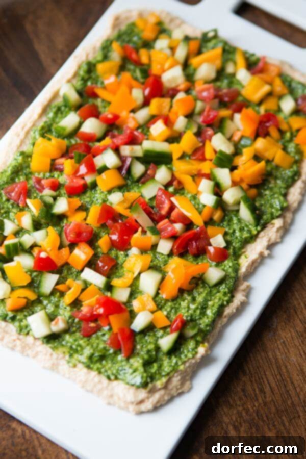8 layer hummus dip with chopped vegetables and cheeses