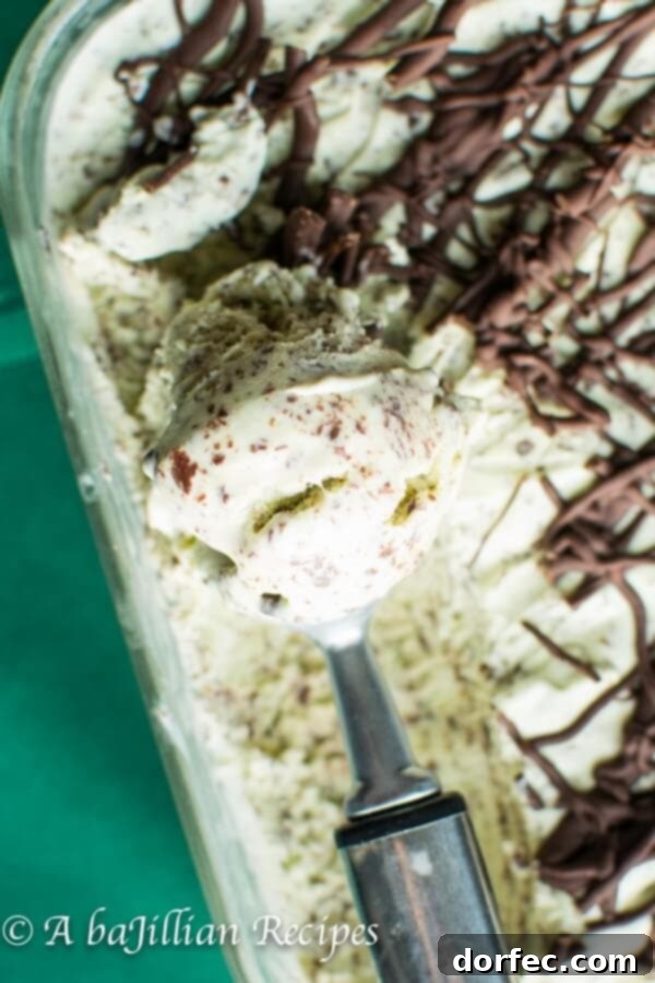 Process of drizzling melted chocolate into churning mint ice cream for stracciatella effect.