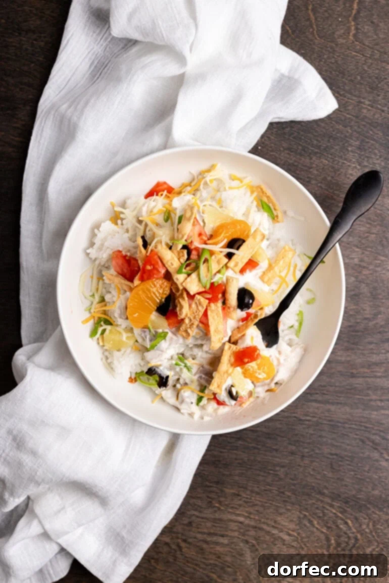 A perfectly portioned serving of Hawaiian Haystacks, presented in a clean white bowl with a base of fluffy rice, crowned with creamy chicken sauce, sweet pineapple chunks, and a sprinkle of crispy wonton strips.