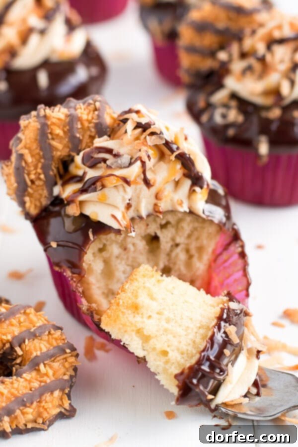A tray of freshly baked Samoa Cupcakes, beautifully frosted and topped with toasted coconut and cookie halves.