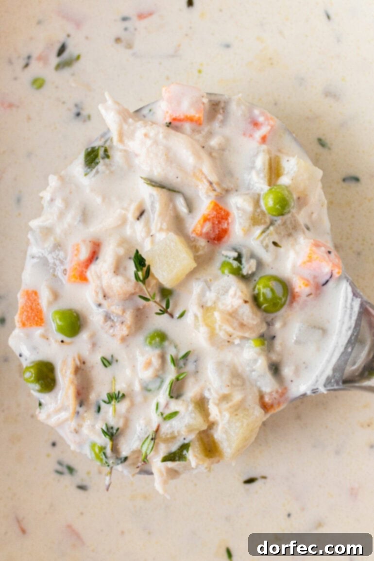 A photo of a big ladle of chicken pot pie soup being lifted from a big pot of soup