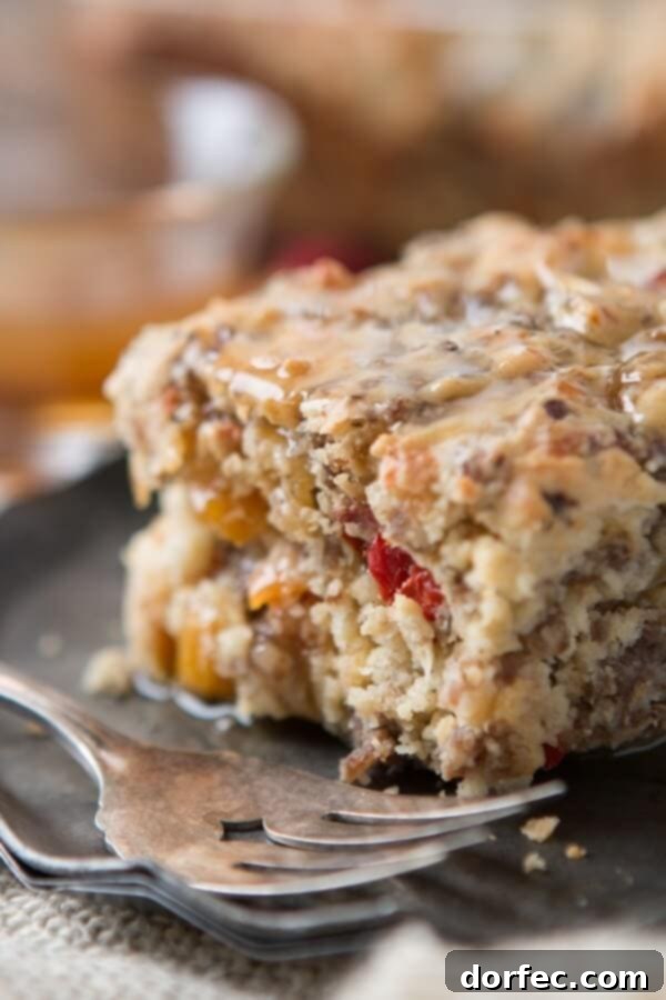 Delightful Southern Sausage Breakfast Cake with Maple Butter Sauce A slice of Southern Sausage Breakfast Cake with a generous drizzle of maple butter sauce, showcasing the golden-brown crust and savory filling of sausage, peppers, and cheese. It's an inviting alternative to traditional sweet breakfasts.