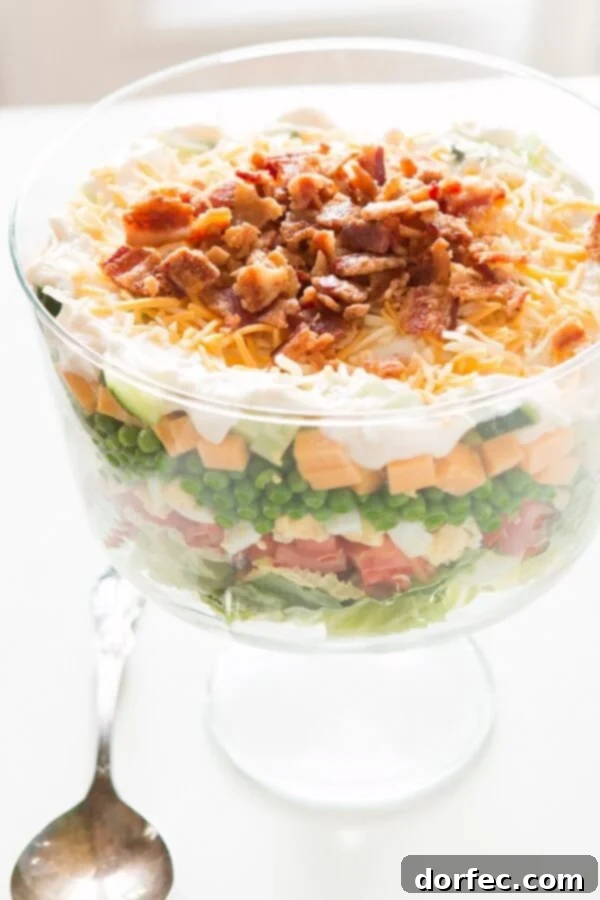 A classic 7 Layer Salad, piled high with fresh ingredients, perfect for any gathering. This recipe features a unique, delicious dressing that sets it apart.