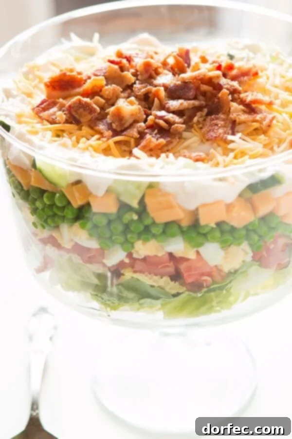 Seven Layer Pea Salad, a classic potluck dish with layers of fresh vegetables, cheese, bacon, and a delightful homemade dressing.