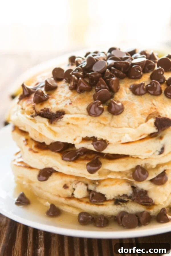 A tall stack of golden-brown homemade chocolate chip pancakes on a white plate, ready to be served for breakfast.