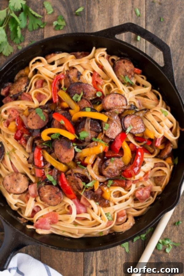 A close-up of creamy Cajun pasta with smoked sausage and colorful bell peppers