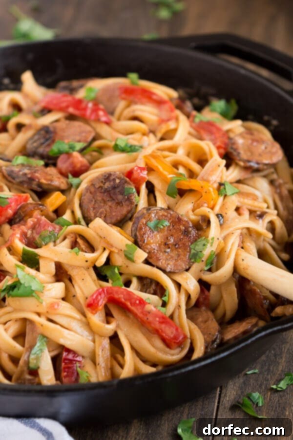 Ingredients for Creamy Cajun Pasta: sliced smoked sausage, colorful bell peppers, and red onion