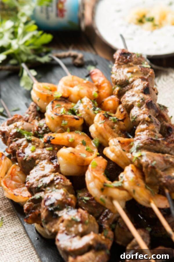 Spicy steak and shrimp kabobs with pina colada sauce on the grill, ready for summer BBQ