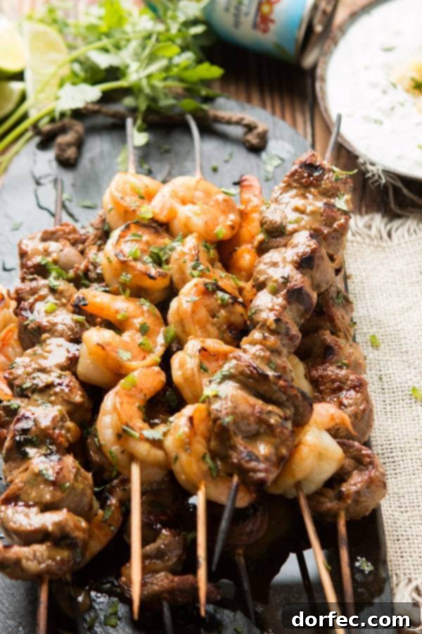 Grilled spicy steak and shrimp kabobs with creamy pina colada sauce, perfect for any BBQ