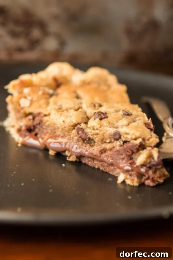 Layers of Deliciousness: Nutella, Dulce de Leche, and Cookie Dough Close-up shot of a baked Nutella Dulce de Leche Chocolate Chip Cookie Pie, revealing the layers of chocolate and caramel.