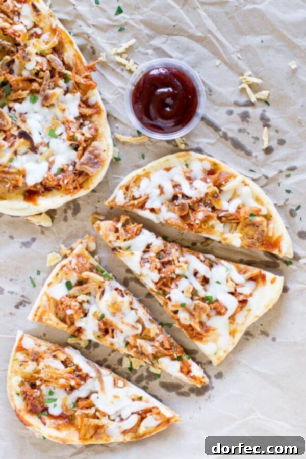 Four delicious pieces of Pulled Pork Pizza with a small cup of barbecue sauce.