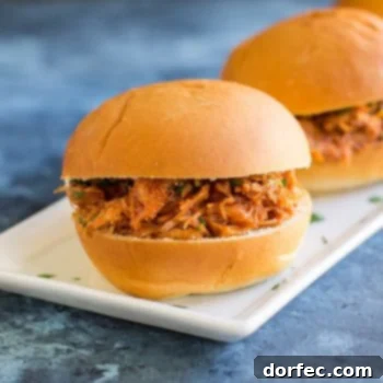 Two Slow Cooker Pulled Pork Sandwiches on a white serving platter.