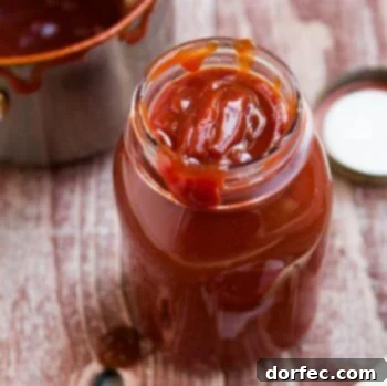 Delicious Homemade BBQ Sauce in a clear glass jar on a wooden table.