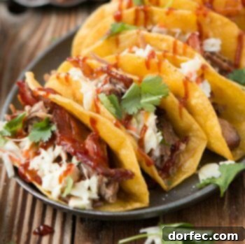 Four BBQ Pulled Pork Tacos with yummy cheese, barbecue and cilantro on a black serving plate on a wooden table.