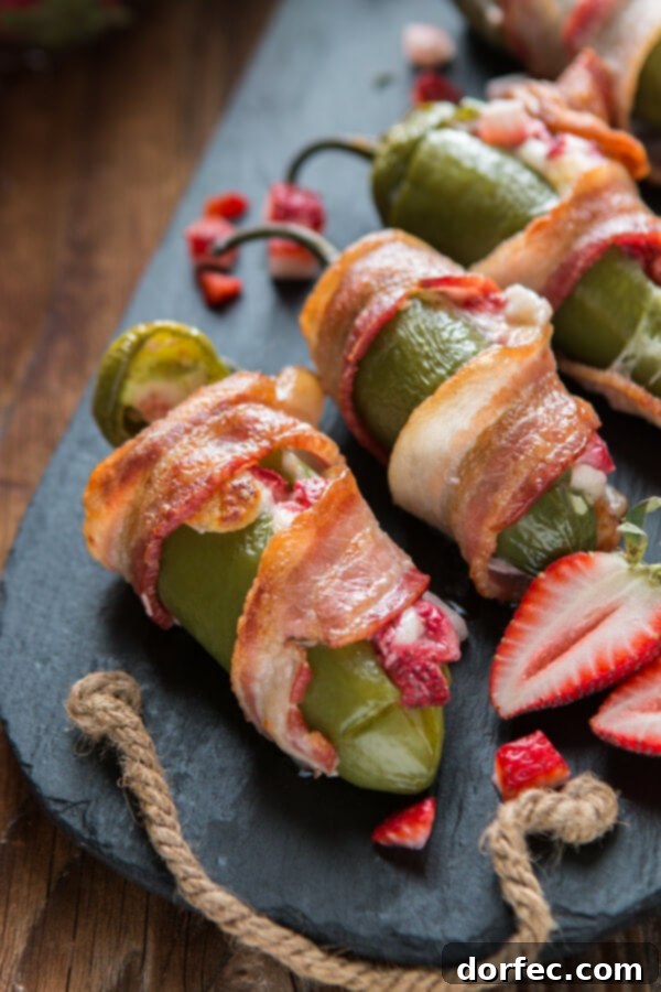 Close-up of a single bacon wrapped strawberry stuffed jalapeno with a succulent strawberry peeking out