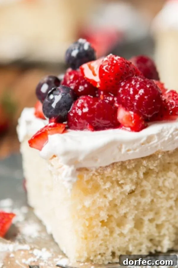 Close-up of Berry White Yogurt Cake slices with fresh berries and cream.