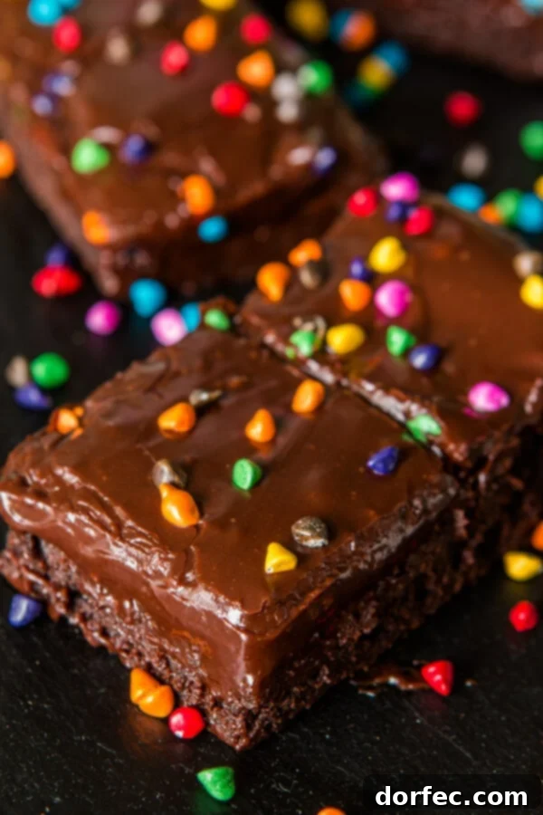 A close-up of a stack of homemade Cosmic Brownies, showcasing their fudgy texture and rainbow candy topping, evoking 90s nostalgia.