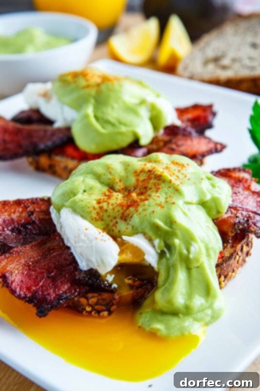 Classic Eggs Benedict elevated with crispy bacon and a vibrant, creamy avocado hollandaise sauce.
