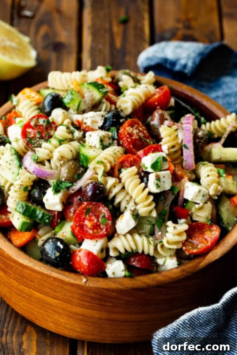 Easy Greek Pasta Salad 6 A rustic, large wooden bowl filled to the brim with colorful Greek pasta salad, showcasing the abundance of fresh ingredients.