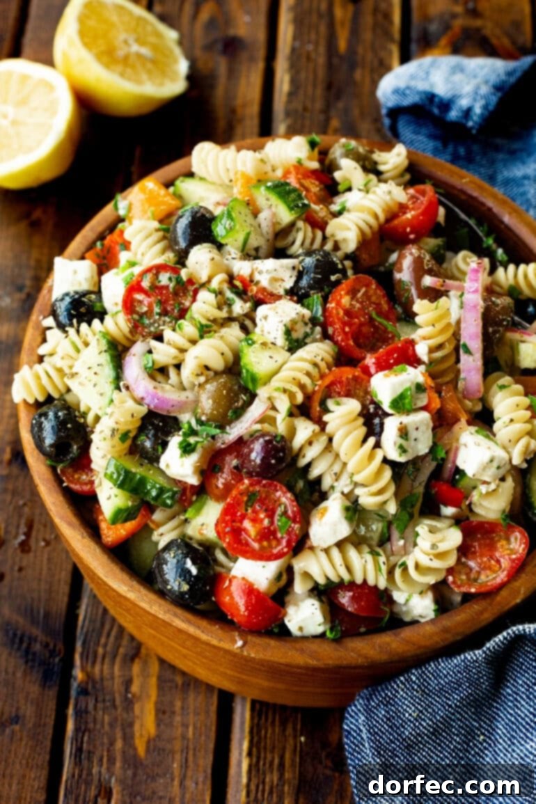 Easy Greek Pasta Salad 7 A full view of a large wooden serving bowl filled with a freshly made Greek pasta salad, ready to be served.