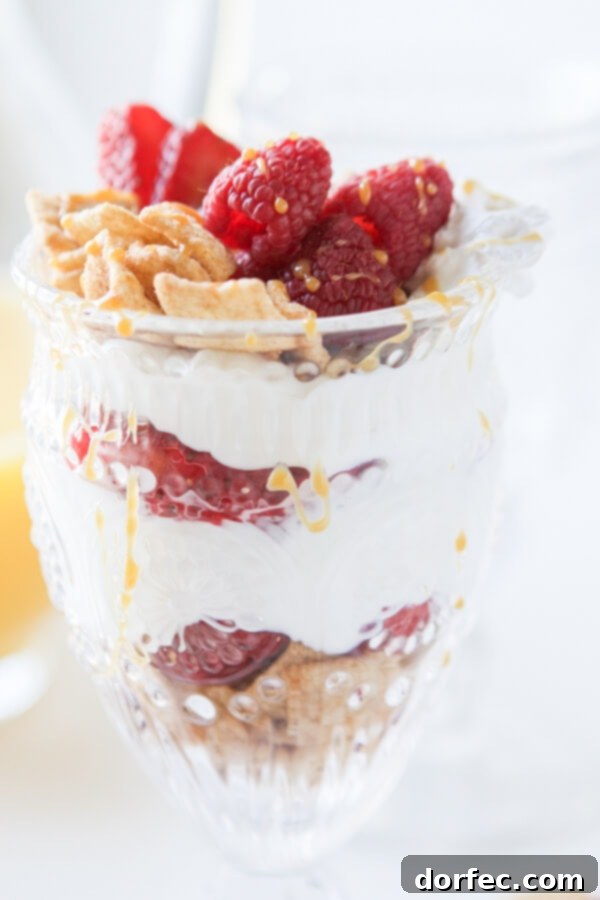 Close-up of a spoon scooping Cinnamon Berry Crisp Yogurt Parfait, highlighting the creamy Greek yogurt and crunchy cereal layers.